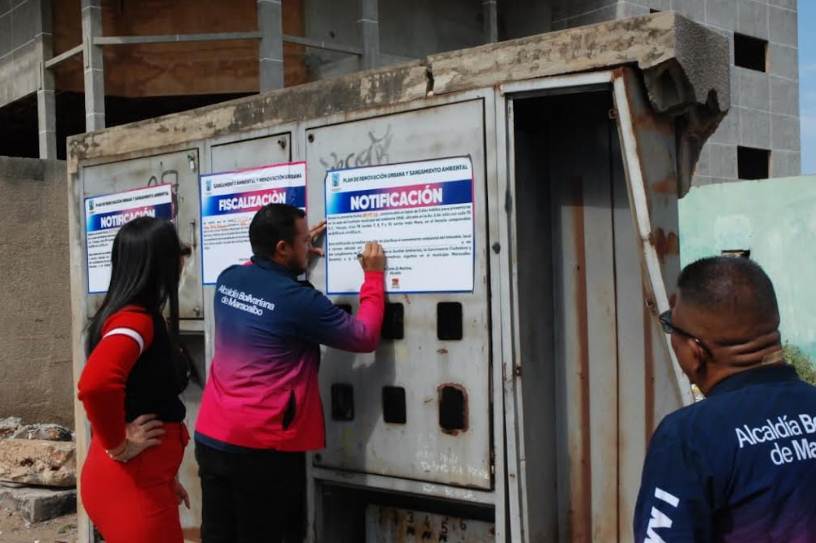 Personal del IMA colocando cartel de intervención en terreno abandonado de Maracaibo