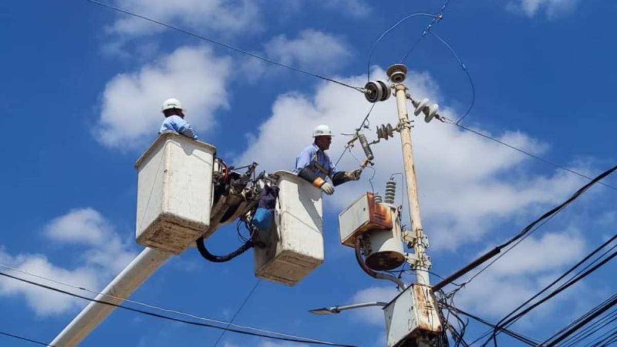 Personal de Corpoelec realizando reparaciones en torres de alta tensión bajo la lluvia
